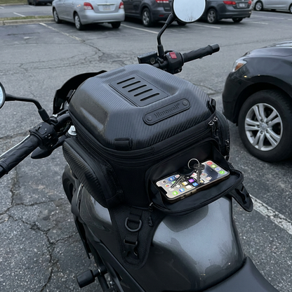 Front pocket open showing phone and keys inside the bag on a tank